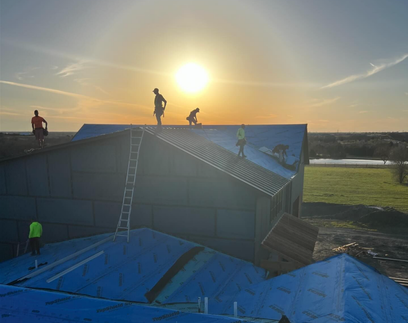 A group of construction workers are working on the roof of a house.