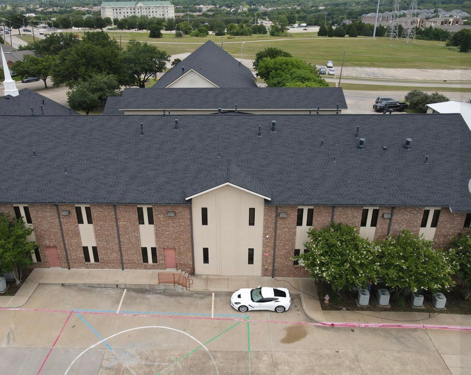 An aerial view of a large brick building with a car parked in front of it.