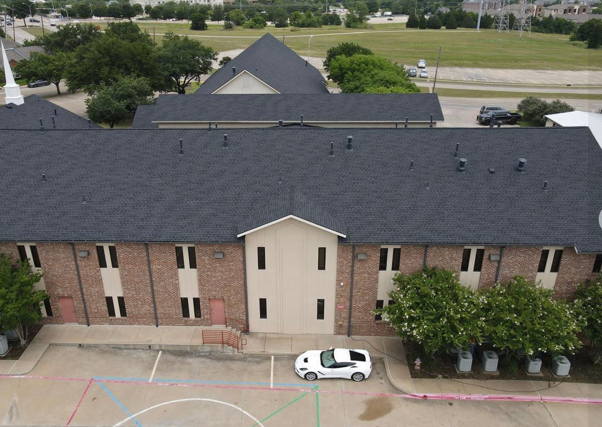 An aerial view of a church with a car parked in front of it