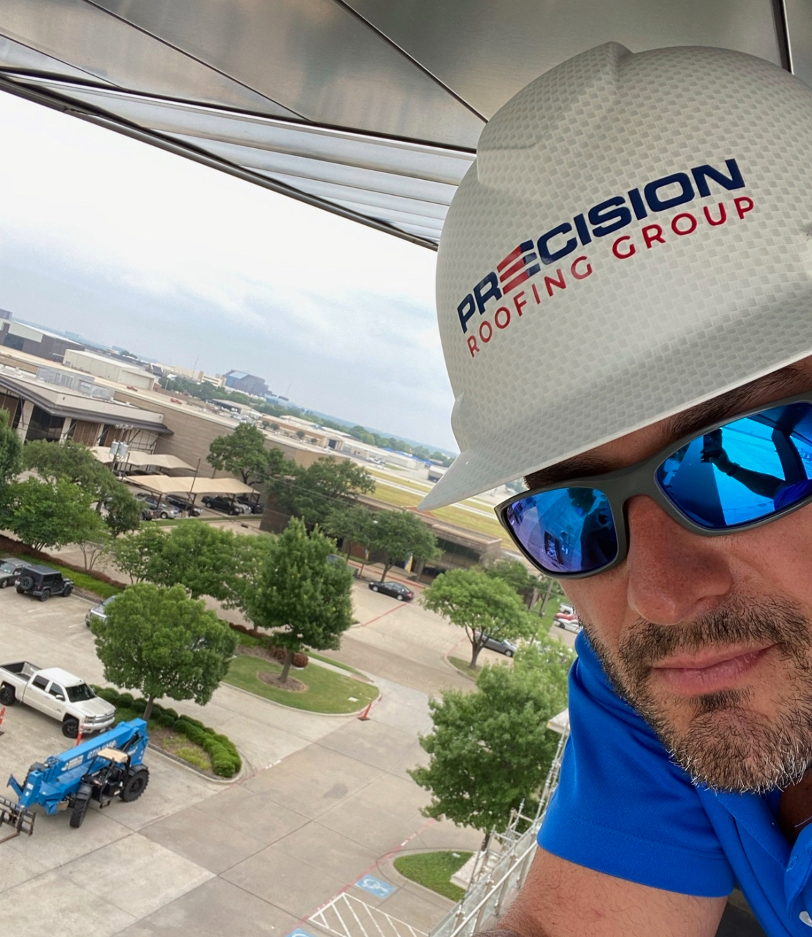 A man wearing a precision roofing group hard hat and sunglasses
