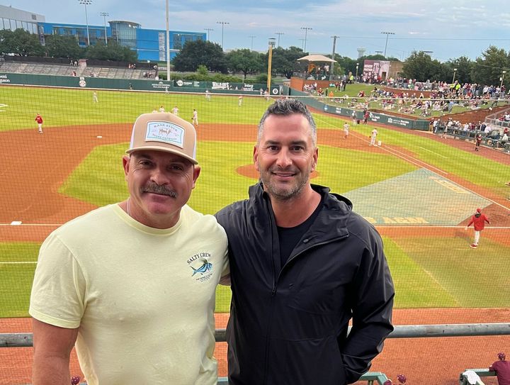 Two men are standing next to each other on a baseball field.