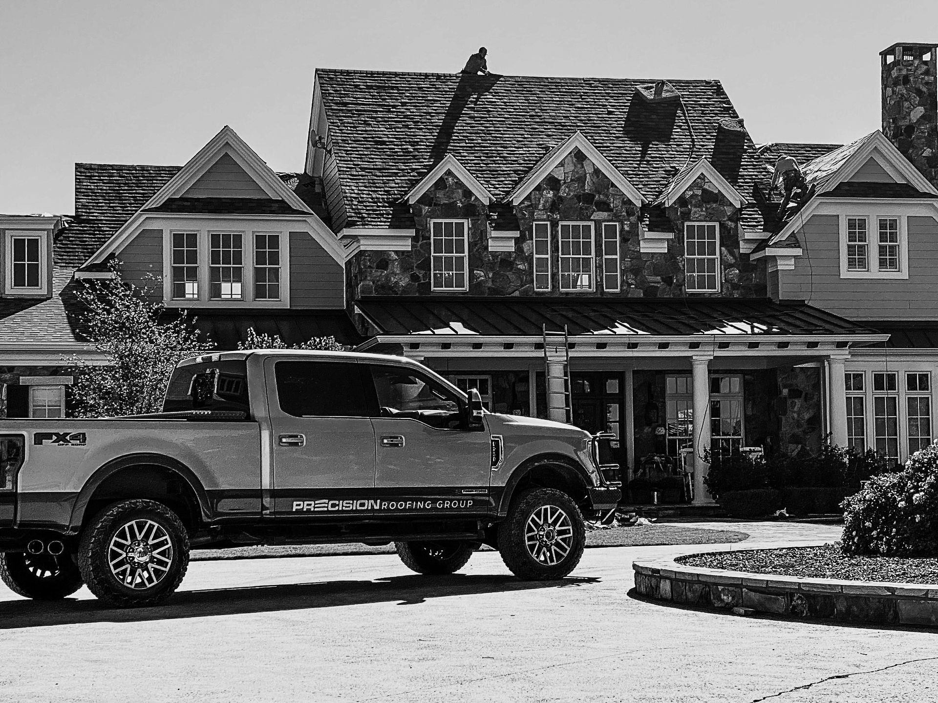 A silver truck is parked in front of a large house.