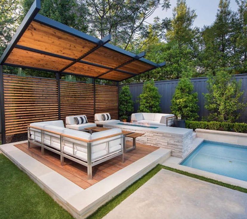 A patio with a pergola , couch , table and a pool.