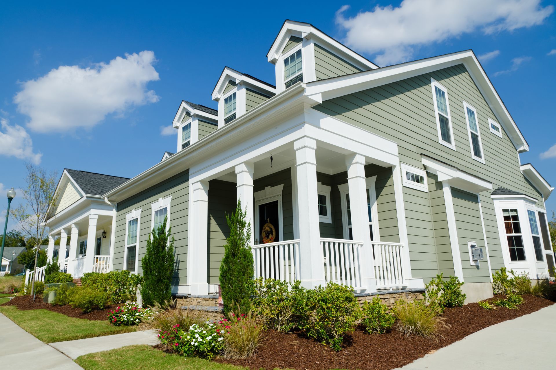 A large green house with white trim and columns