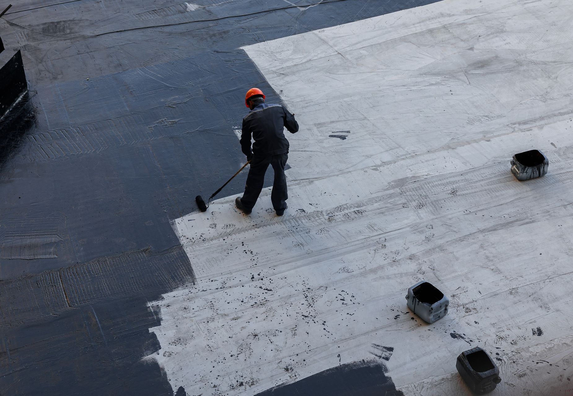 A man is painting a roof with a roller.