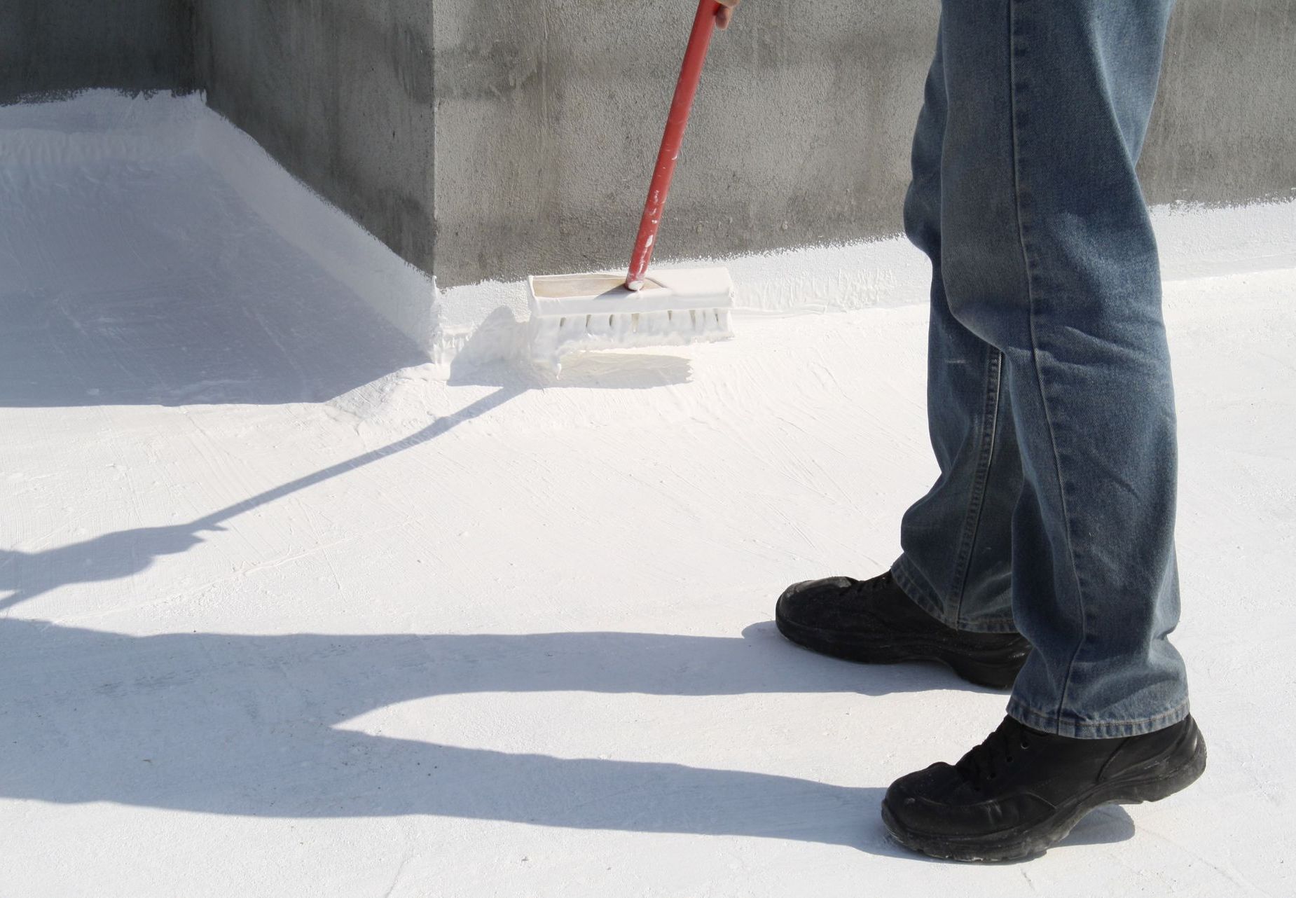 A man is painting a roof with a roller.