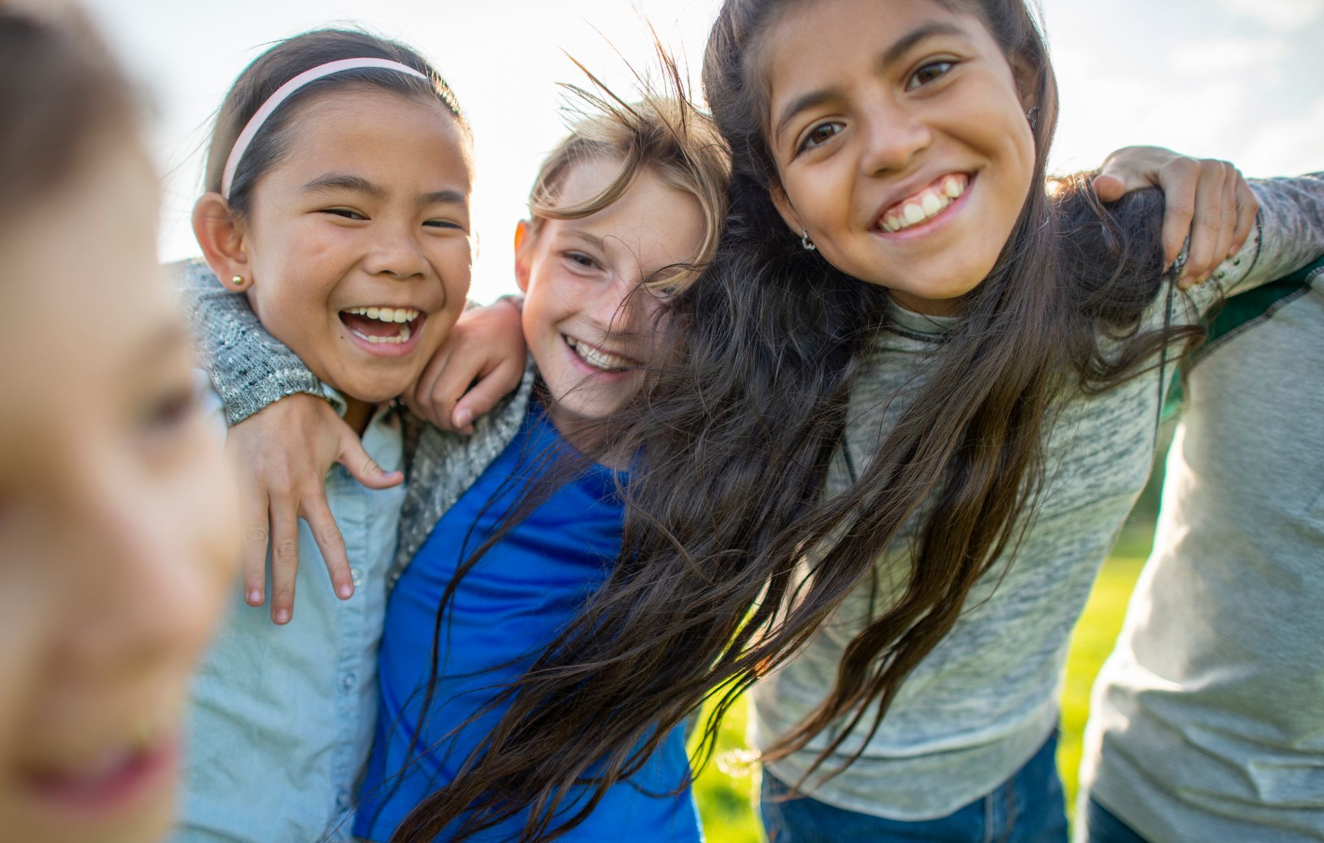 A group of young girls are hugging each other and smiling.