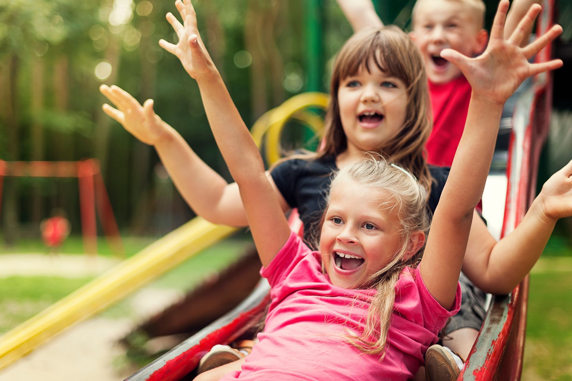 Group of children sliding down a playground slide.