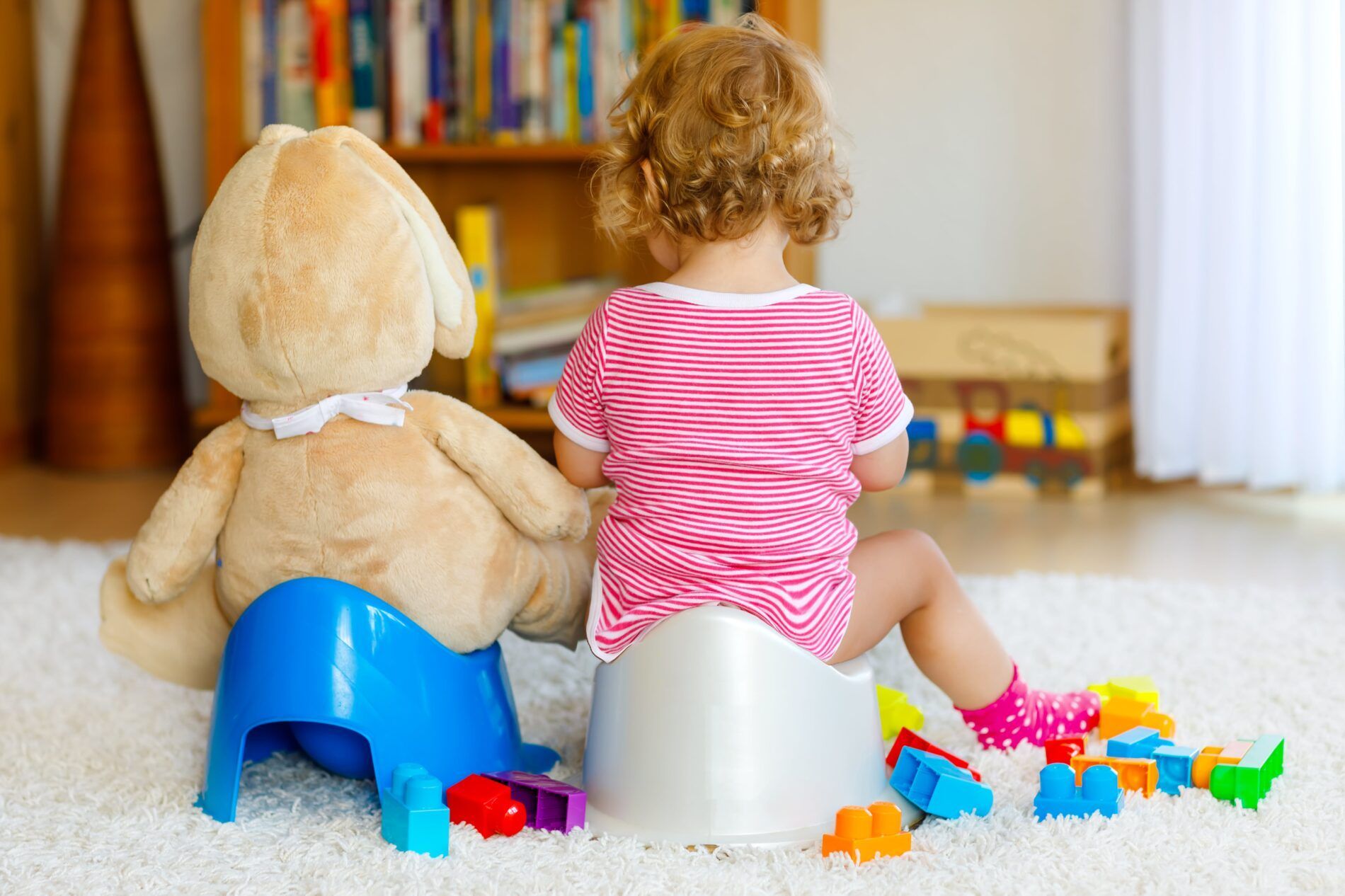 Back of child and teddy bear sitting on stools.