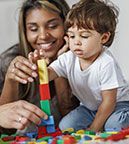 A mother and young boy are playing with colorful blocks.