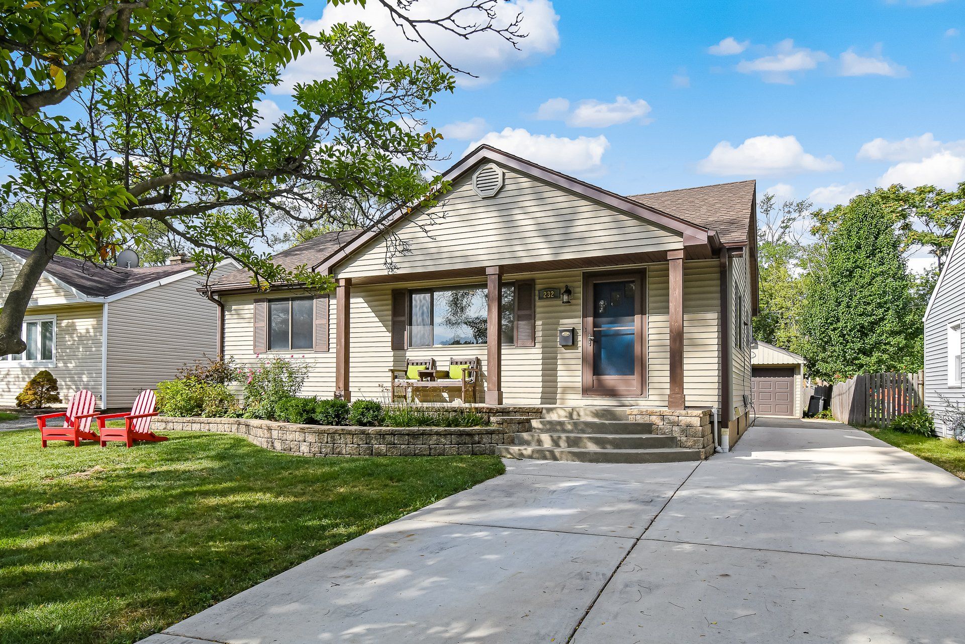 A house with a porch and lawn chairs in front of it