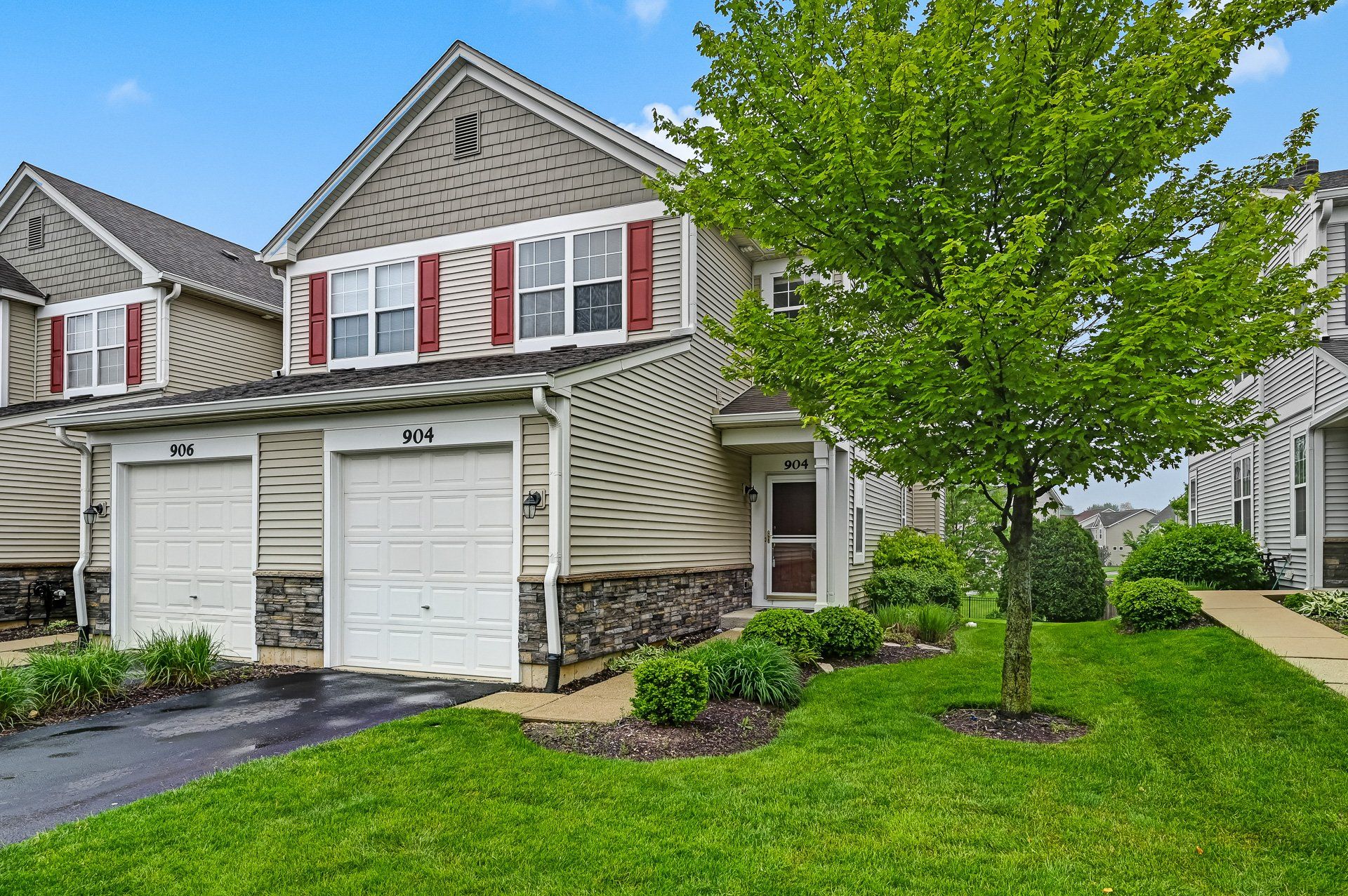 A house with two garages and a tree in front of it.