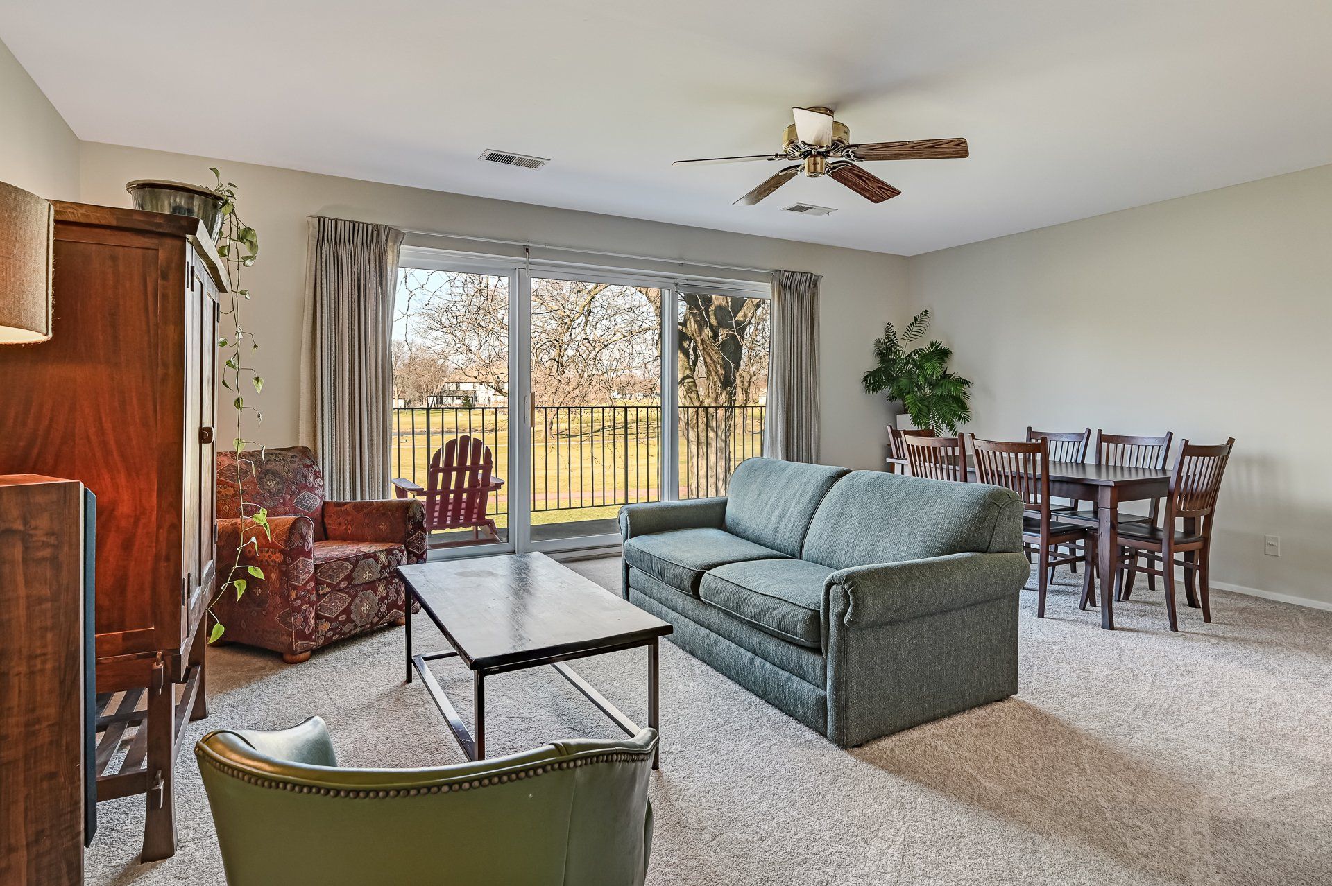 A living room with a couch , chair , table and ceiling fan.