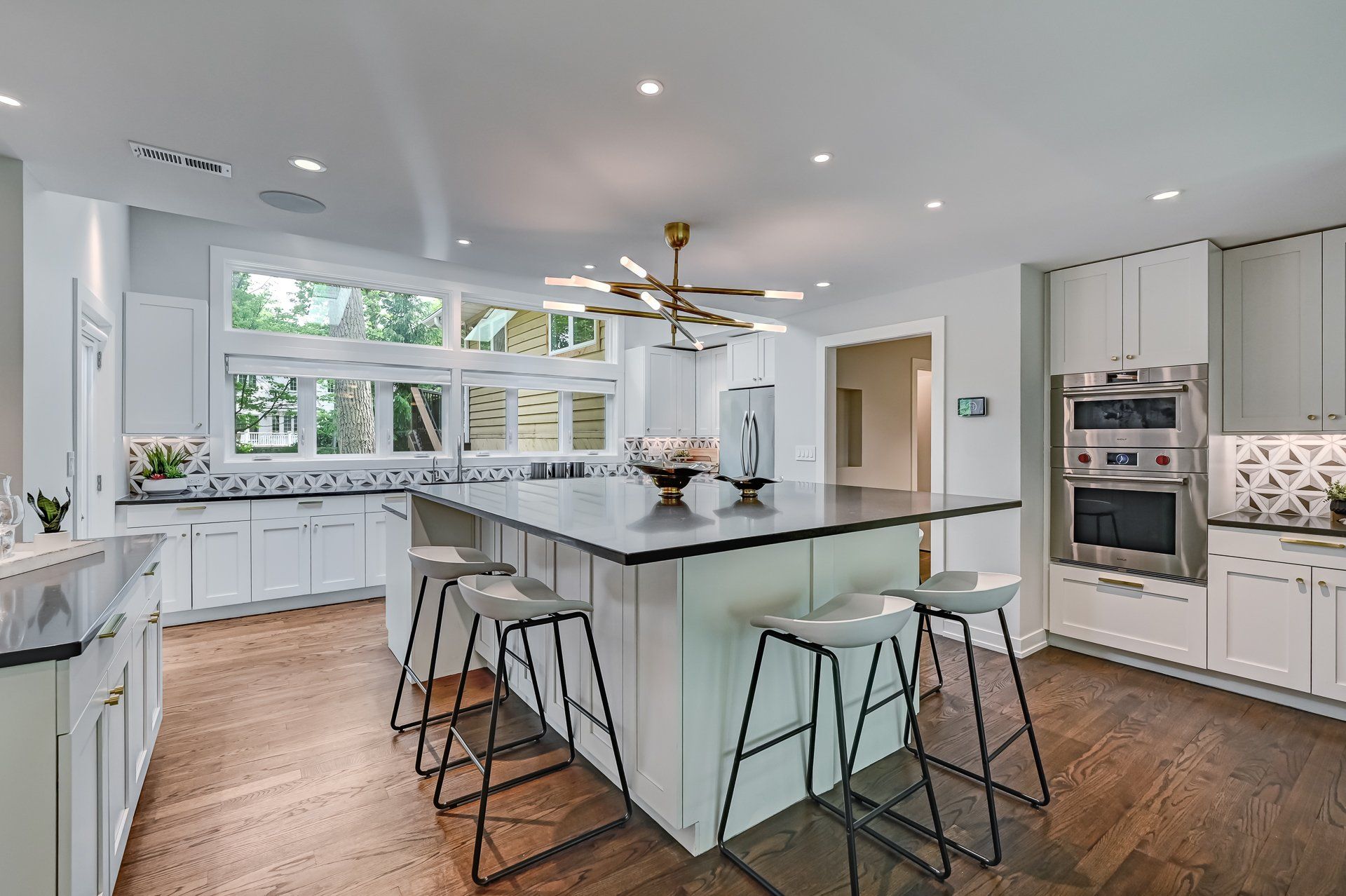 A kitchen with white cabinets and stools and a large island in the middle.