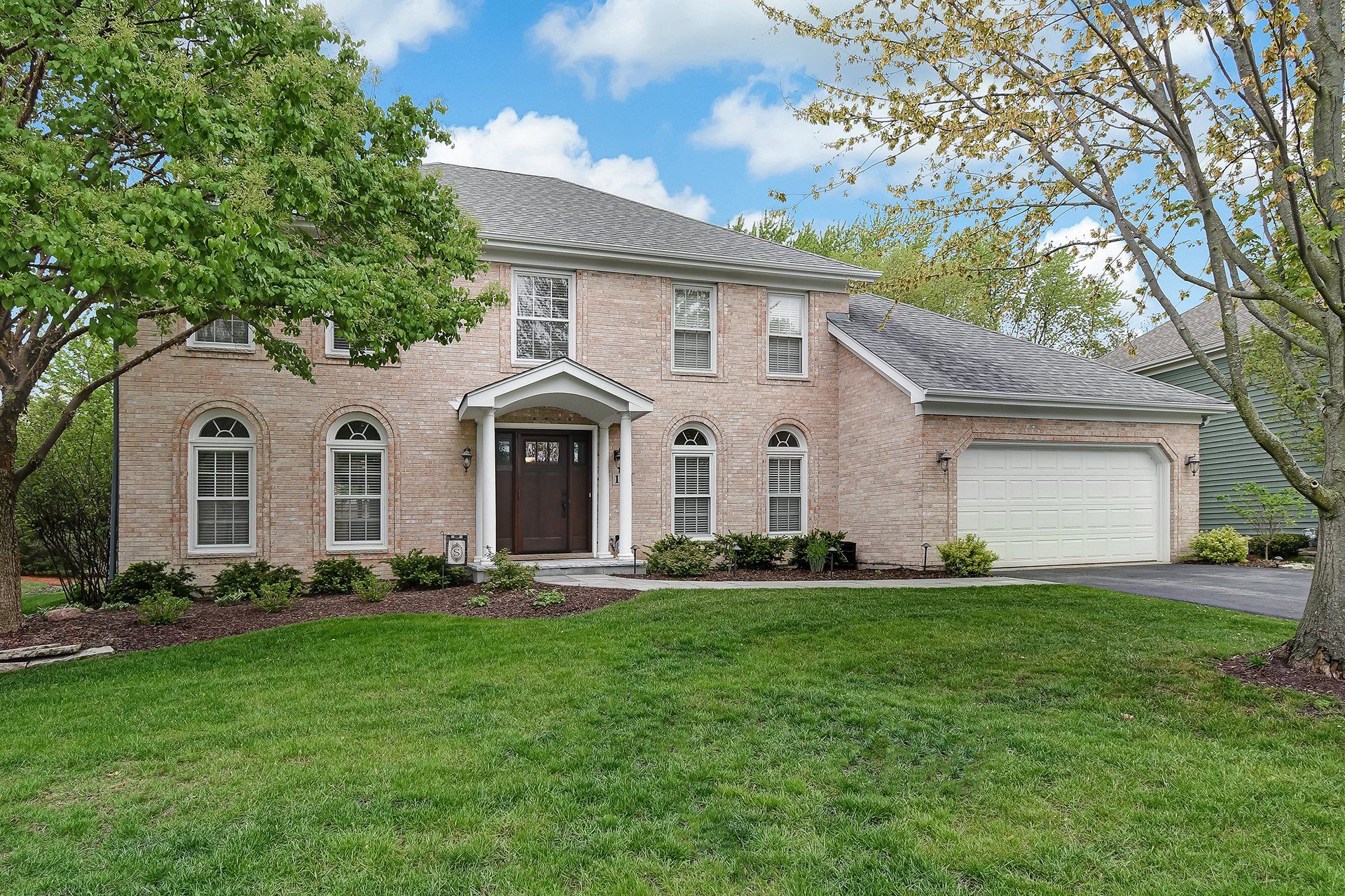 A large brick house with a large lawn in front of it.