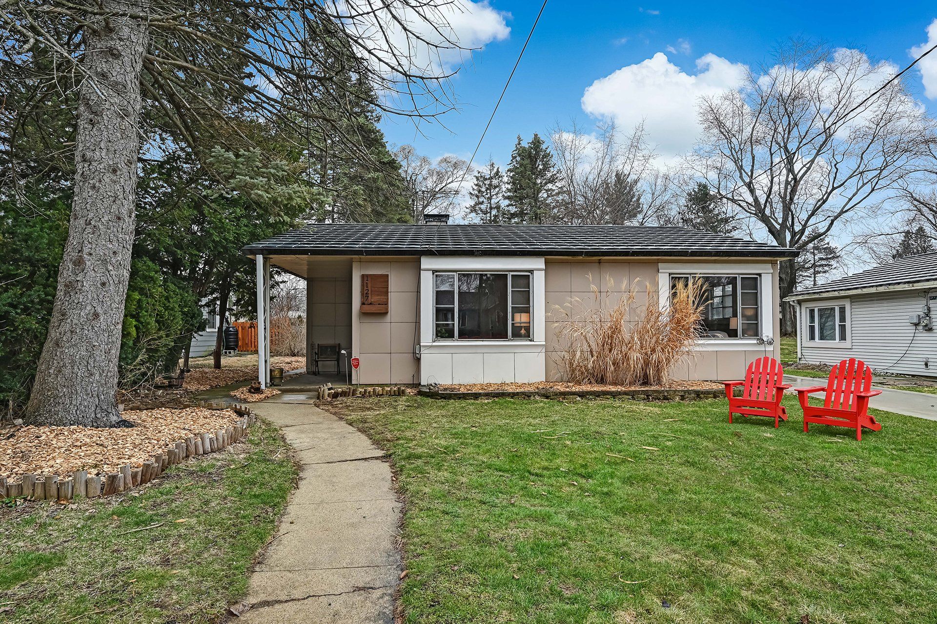 A small house with two red chairs in front of it.