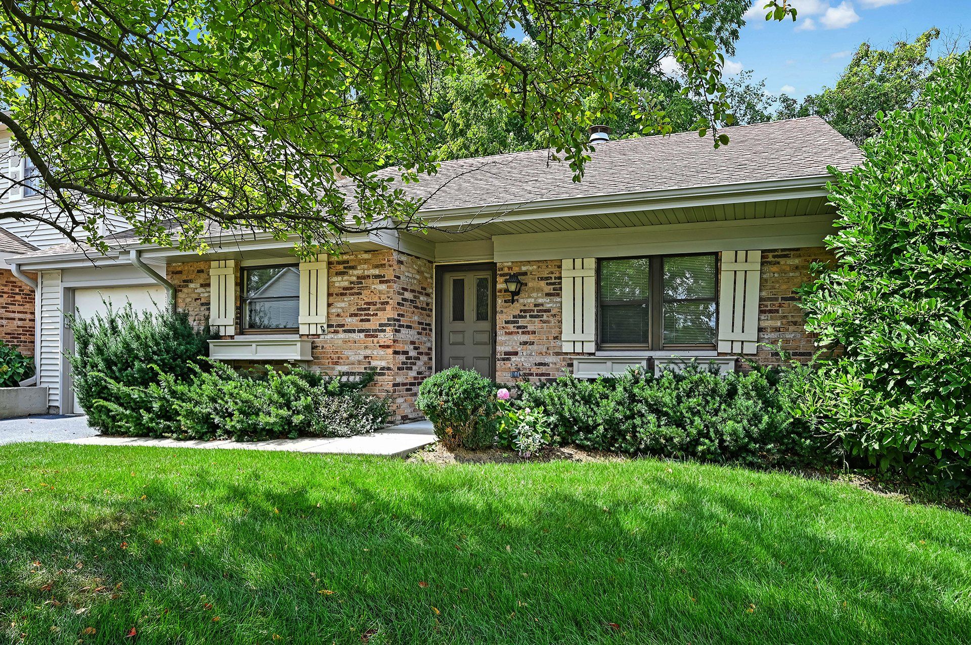 A brick house with a lush green lawn in front of it.