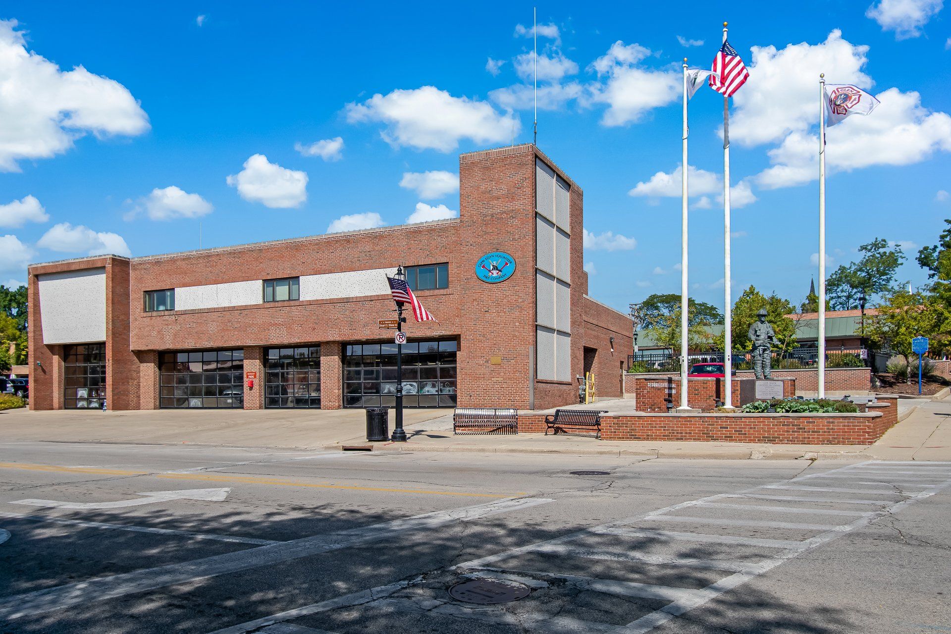 A large brick building with three american flags flying in front of it.