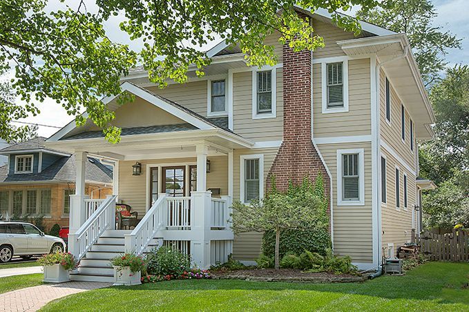A large house with a brick chimney is sitting on top of a lush green lawn.