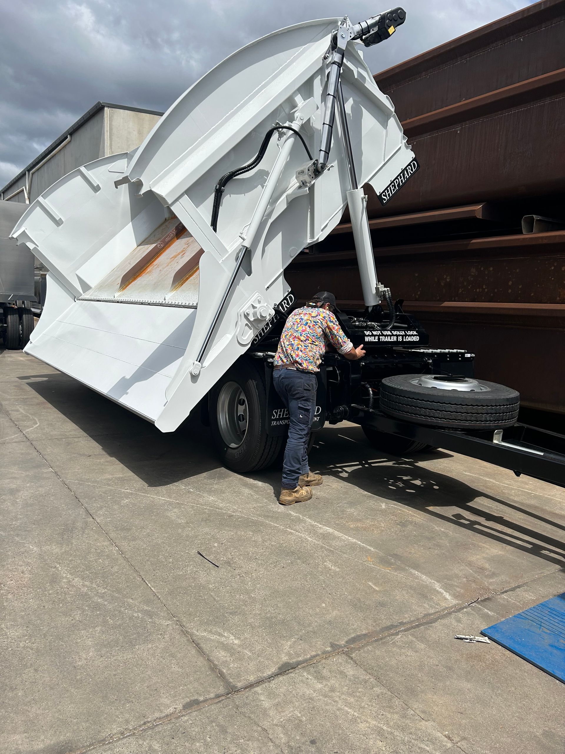A man is working on a dump truck in a parking lot.