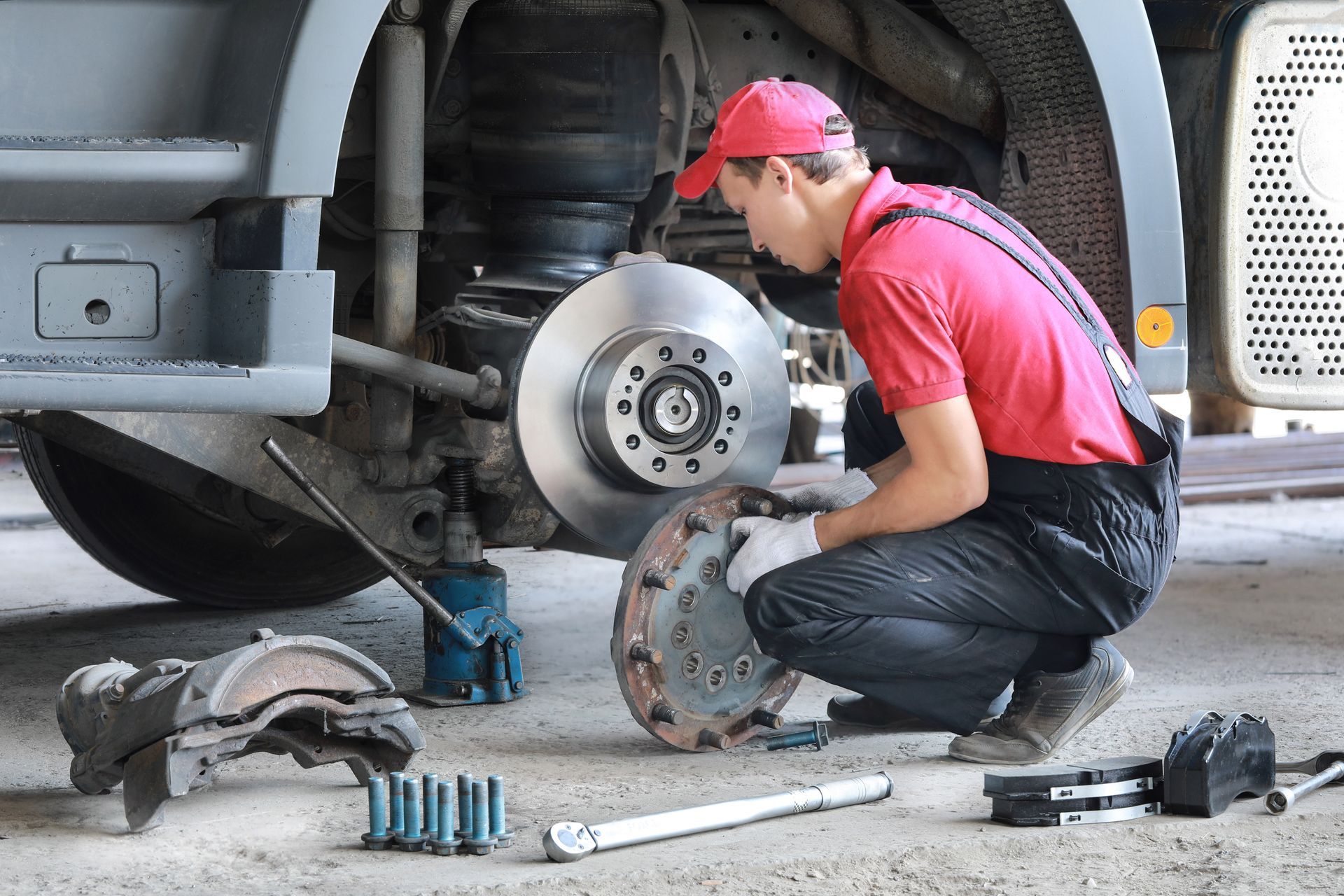 A mechanic repairs a truck. He replaces a brake disc and pads. A mechanic repairs a truck. He replaces a brake disc and pads.