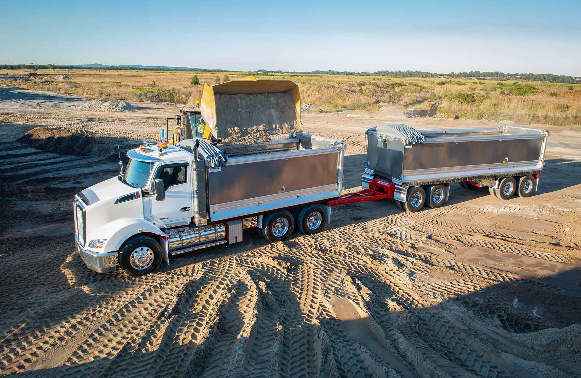 A dump truck is driving through a dirt field.