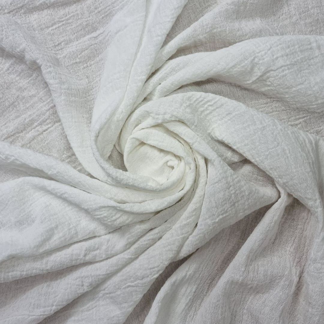 Una toalla blanca está envuelta en un remolino sobre una mesa.