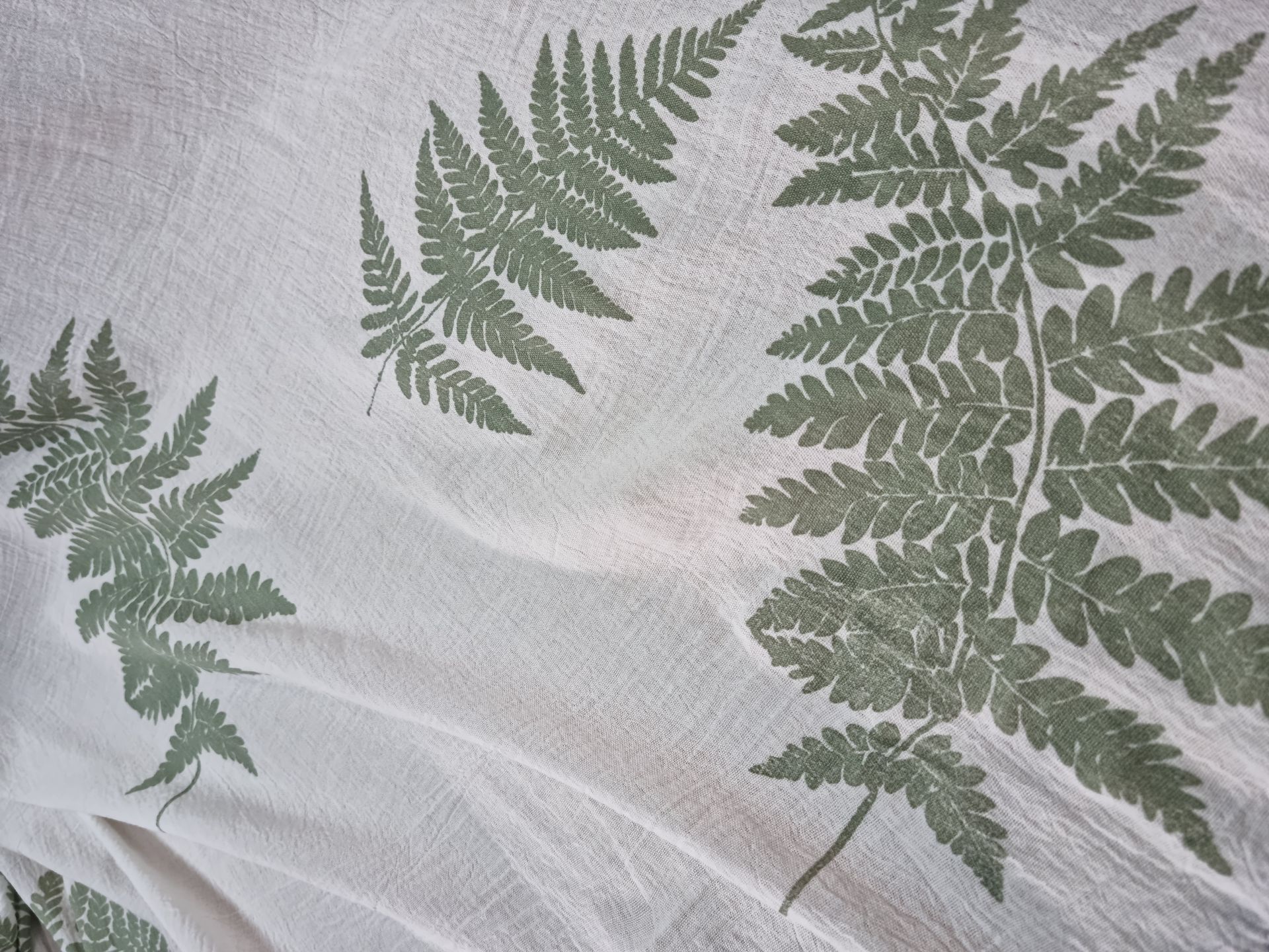 Un primer plano de una toalla blanca con hojas de helecho encima.