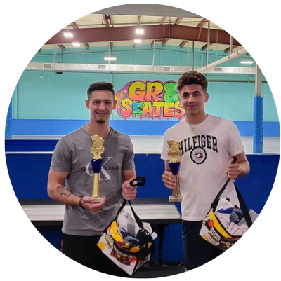 Two men are holding trophies in front of a sign that says gro skates