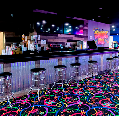 A bar with colorful stools and a neon carpet