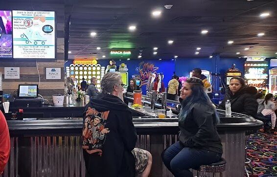 A man and a woman are sitting at a bar in a bowling alley.