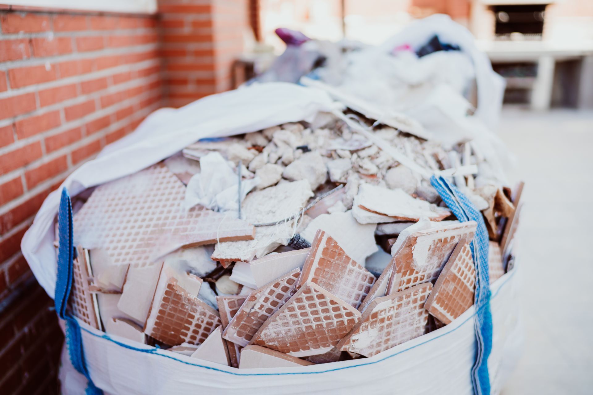 A bag filled with broken tiles is sitting in front of a brick wall.