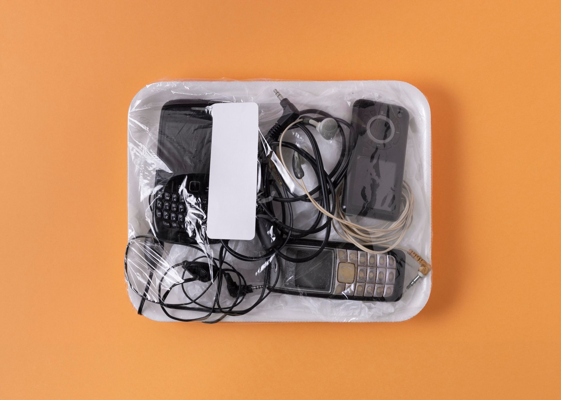A styrofoam tray filled with electronics on an orange background.