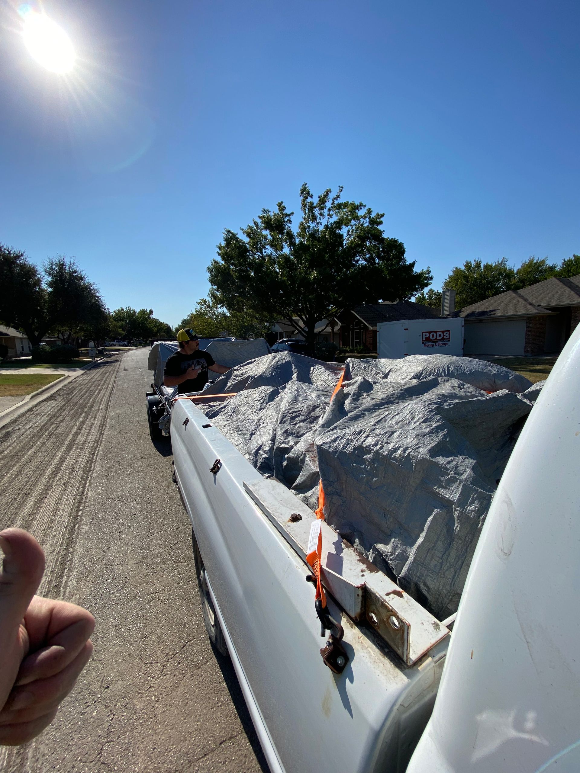 A man is standing in the back of a truck full of rocks.