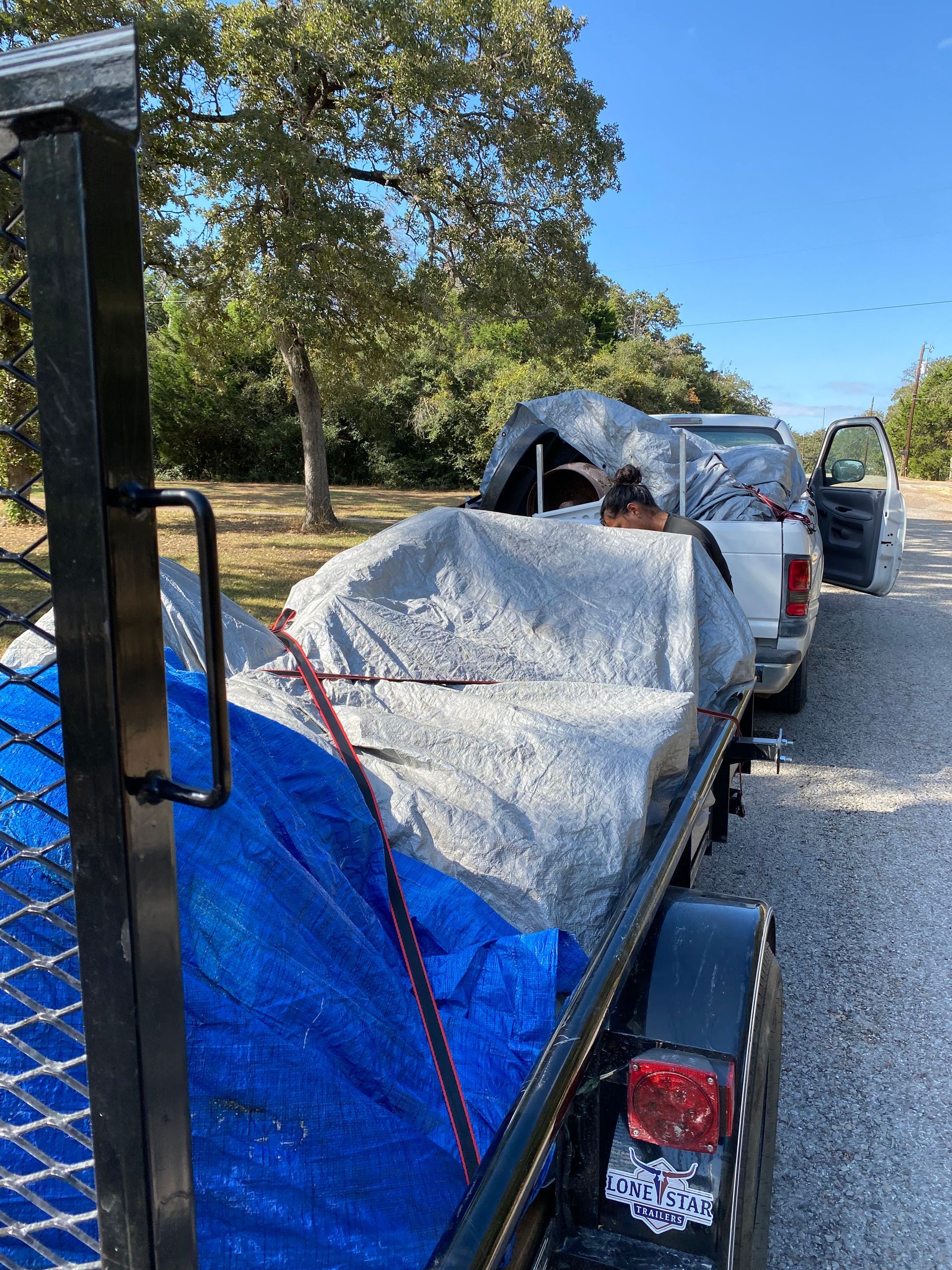 A trailer with a tarp on it is parked on the side of the road.