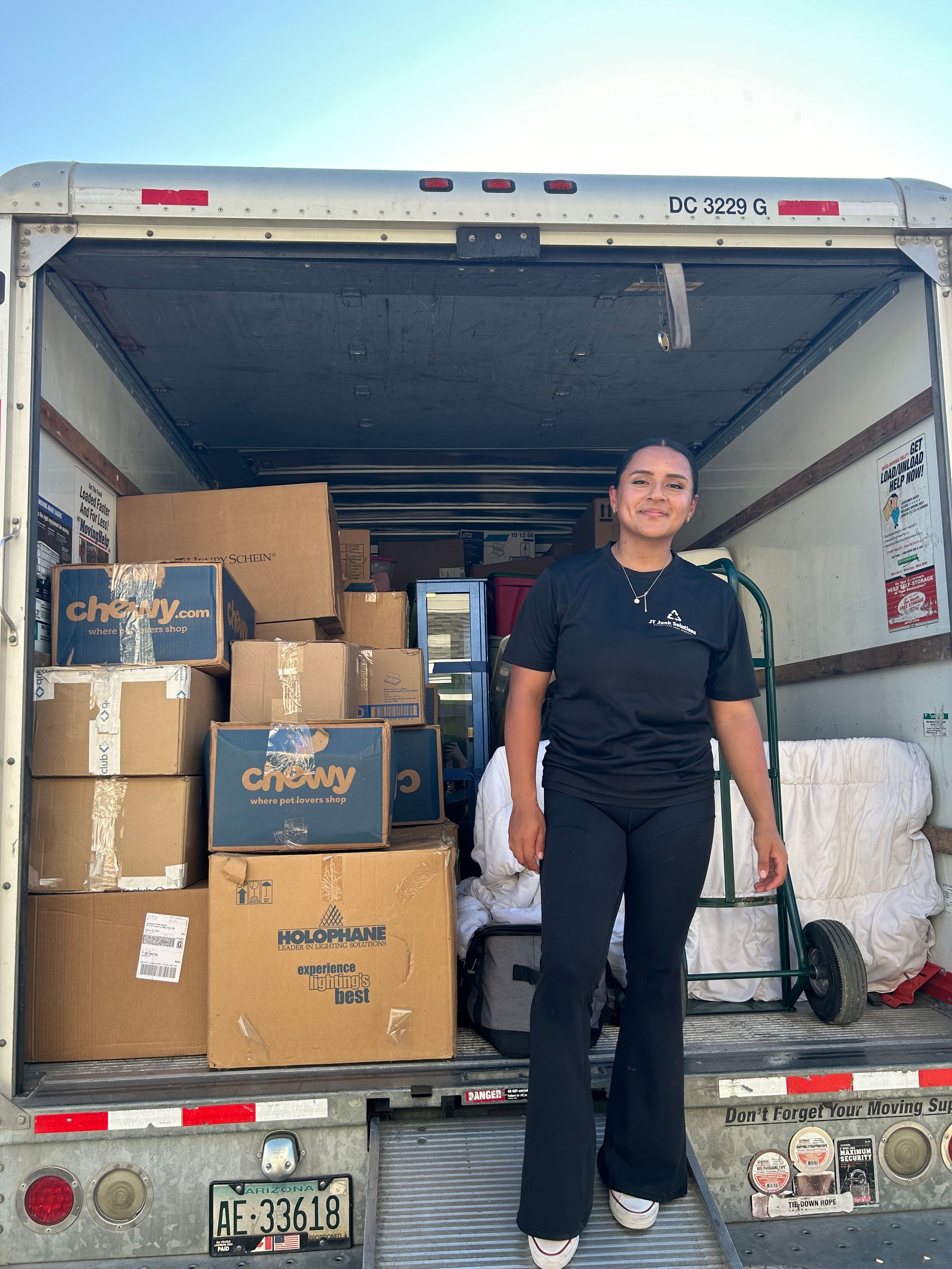 A woman is standing in the back of a moving truck filled with boxes.