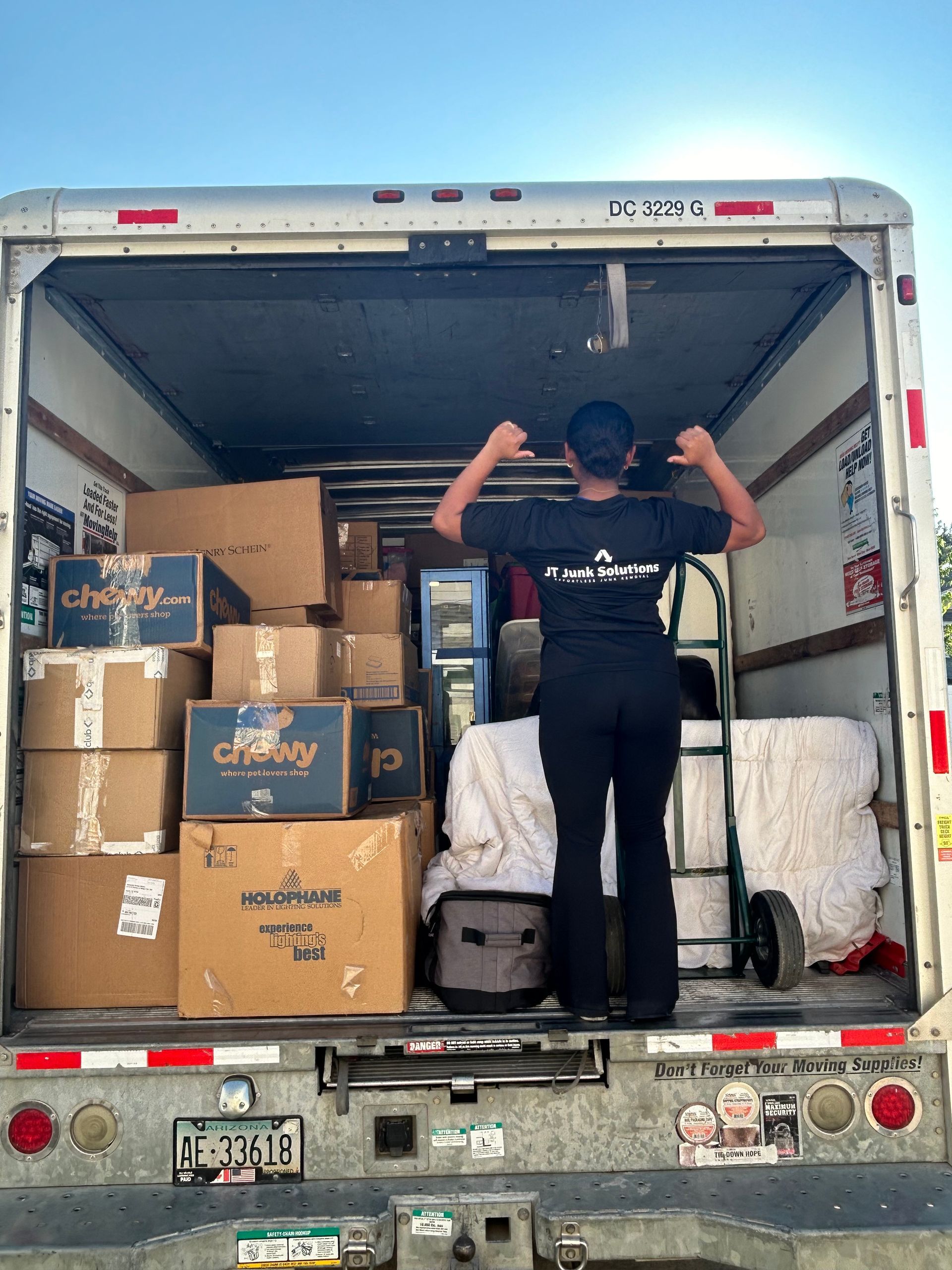 A woman is standing in the back of a moving truck filled with boxes.