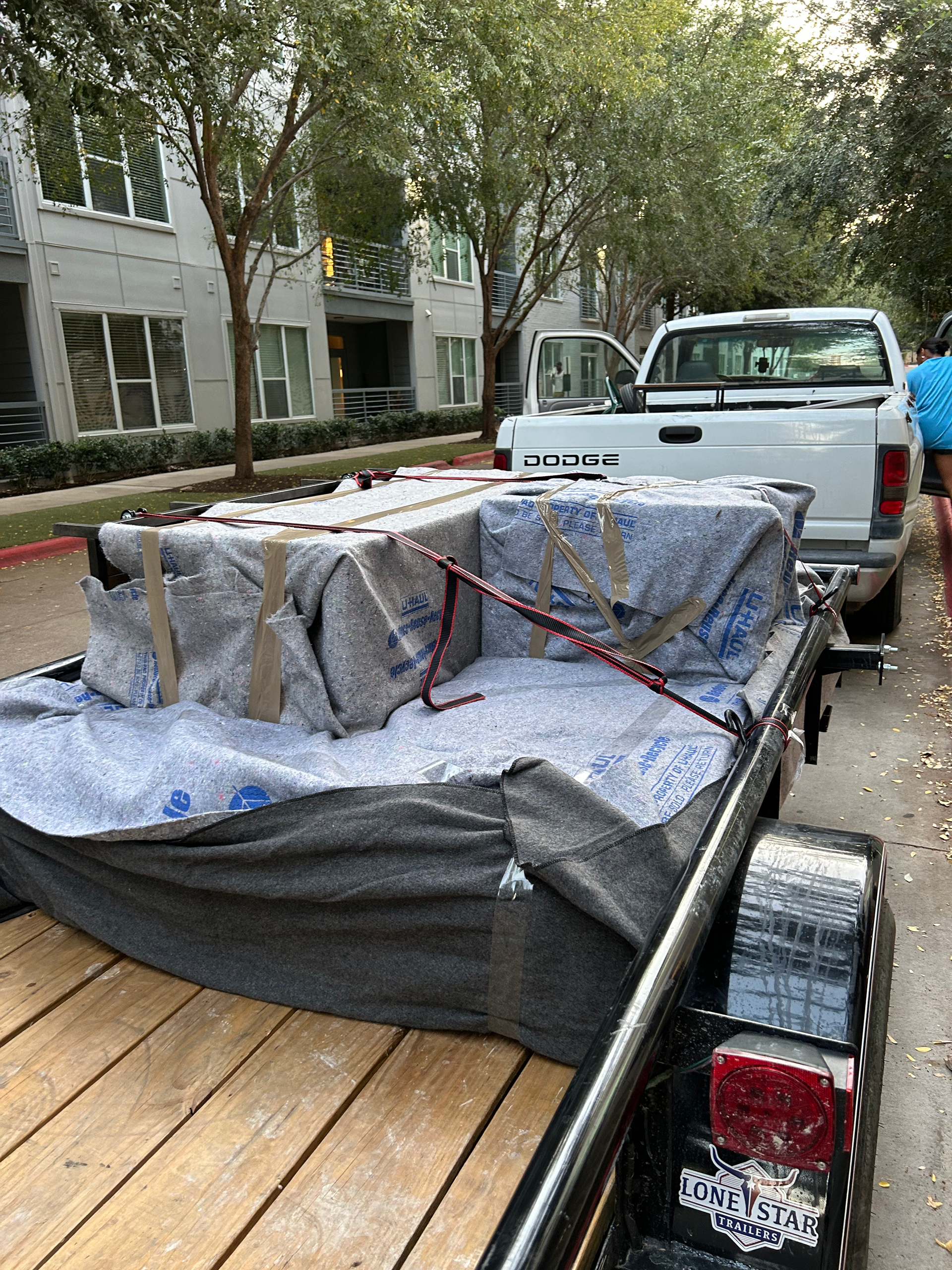 A trailer with a ramp attached to it is being towed by a car.