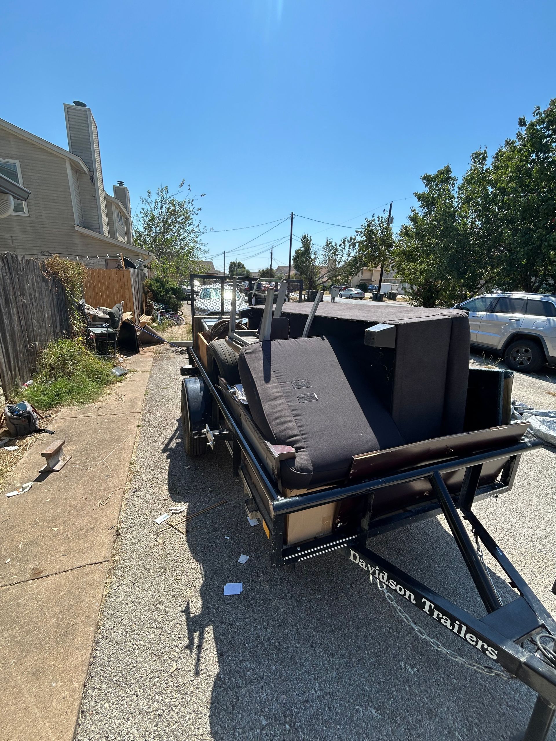 A trailer with a couch on it is parked on the side of the road.