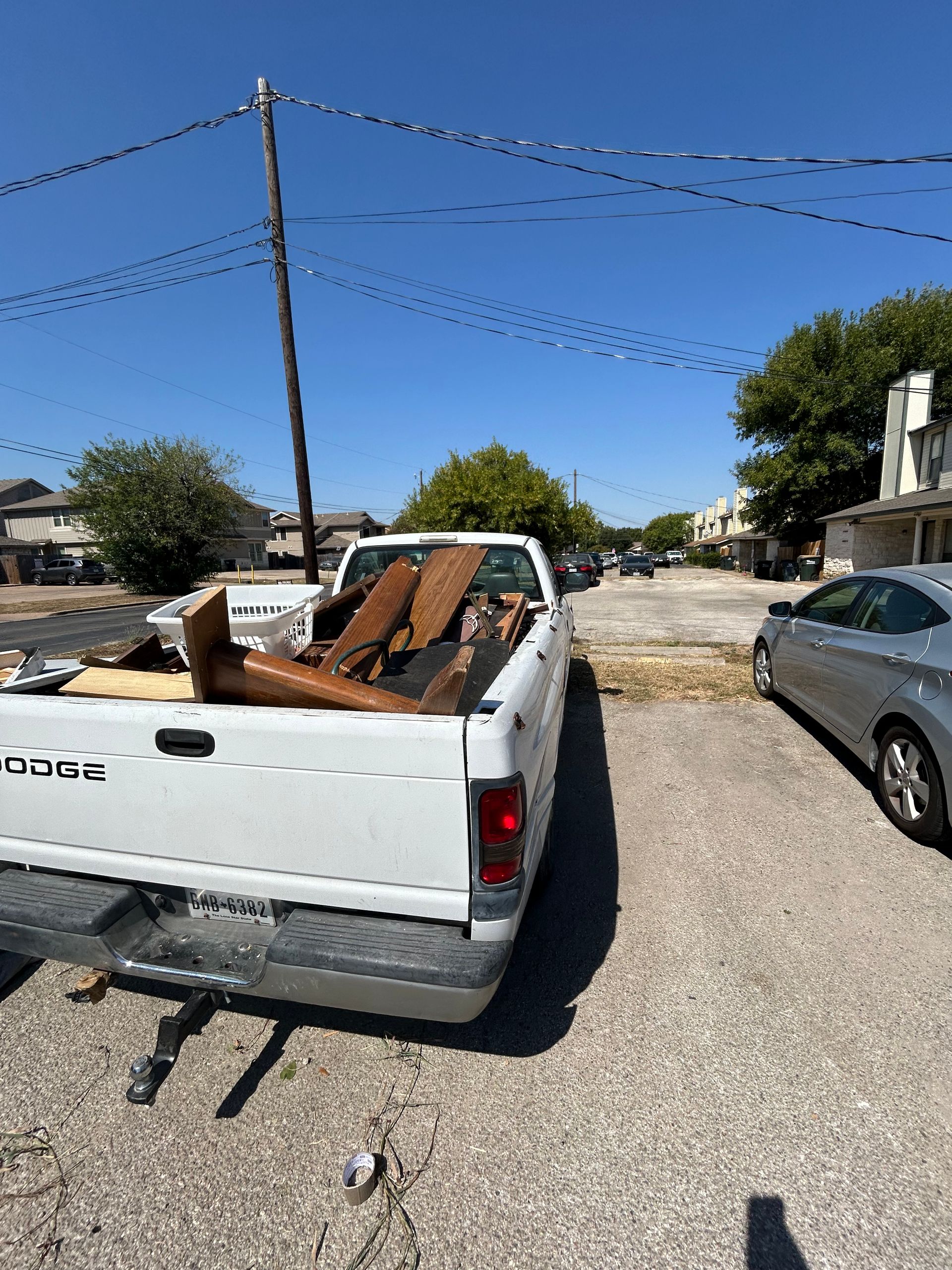 A white truck with a bunch of wood in the back is parked in a parking lot.