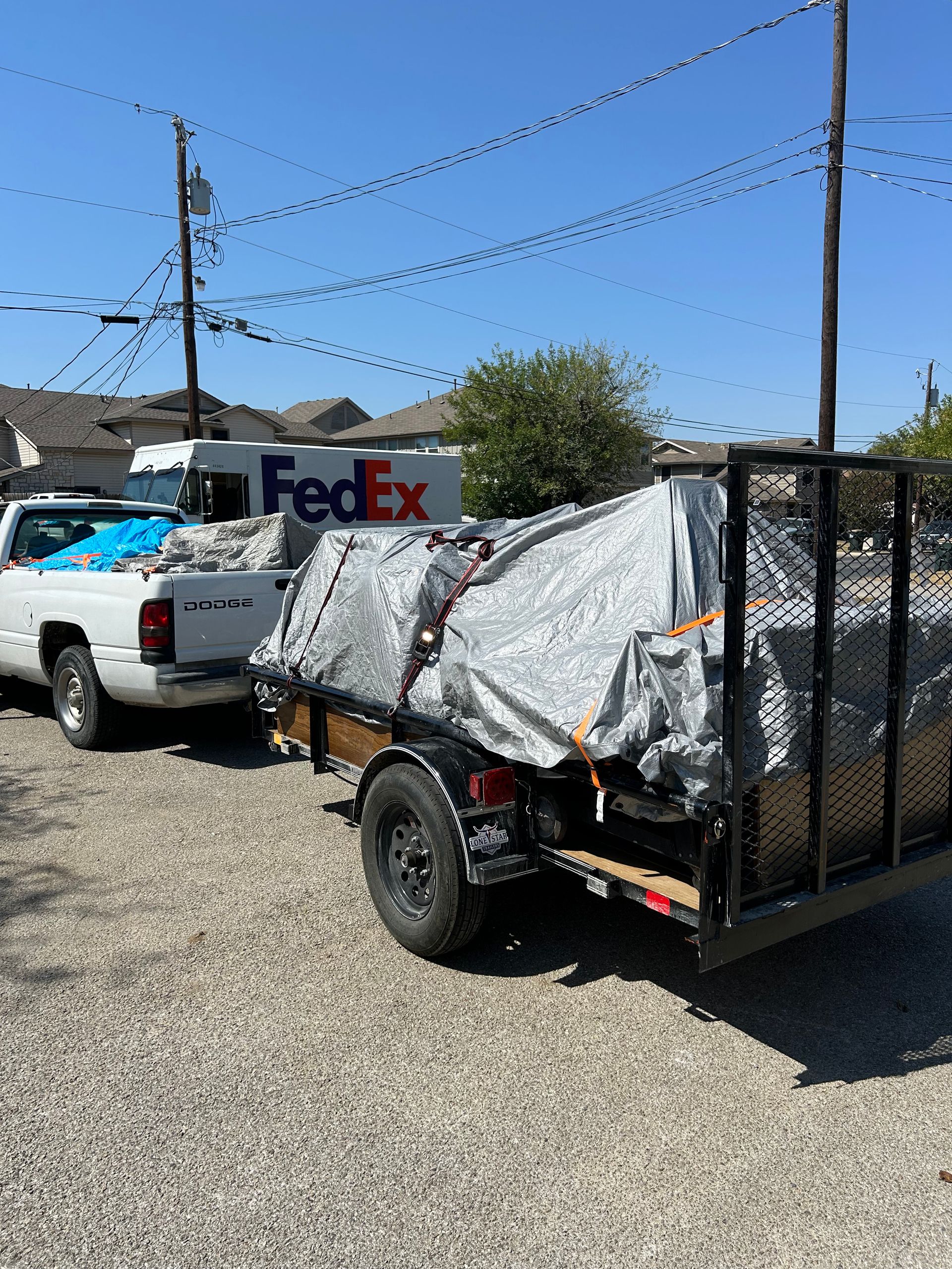 A fedex truck is parked next to a trailer.