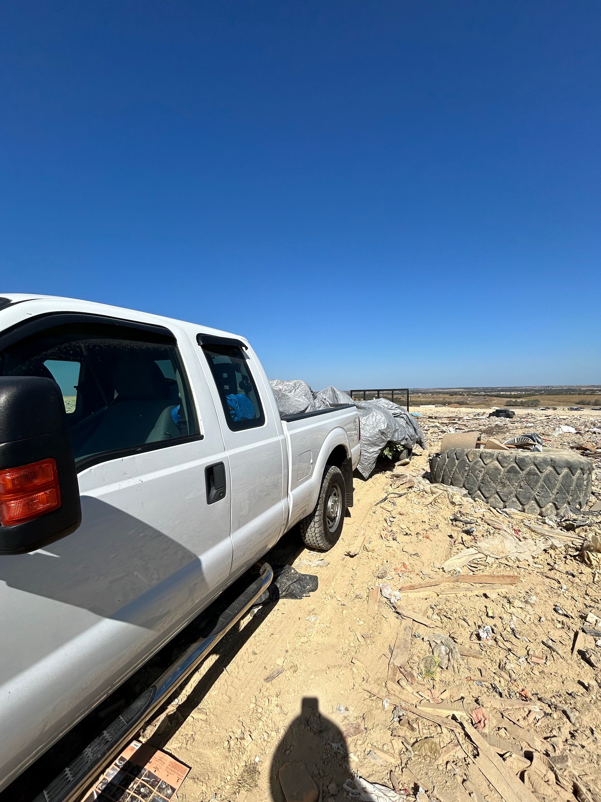 A white truck is parked in the sand on a dirt road.