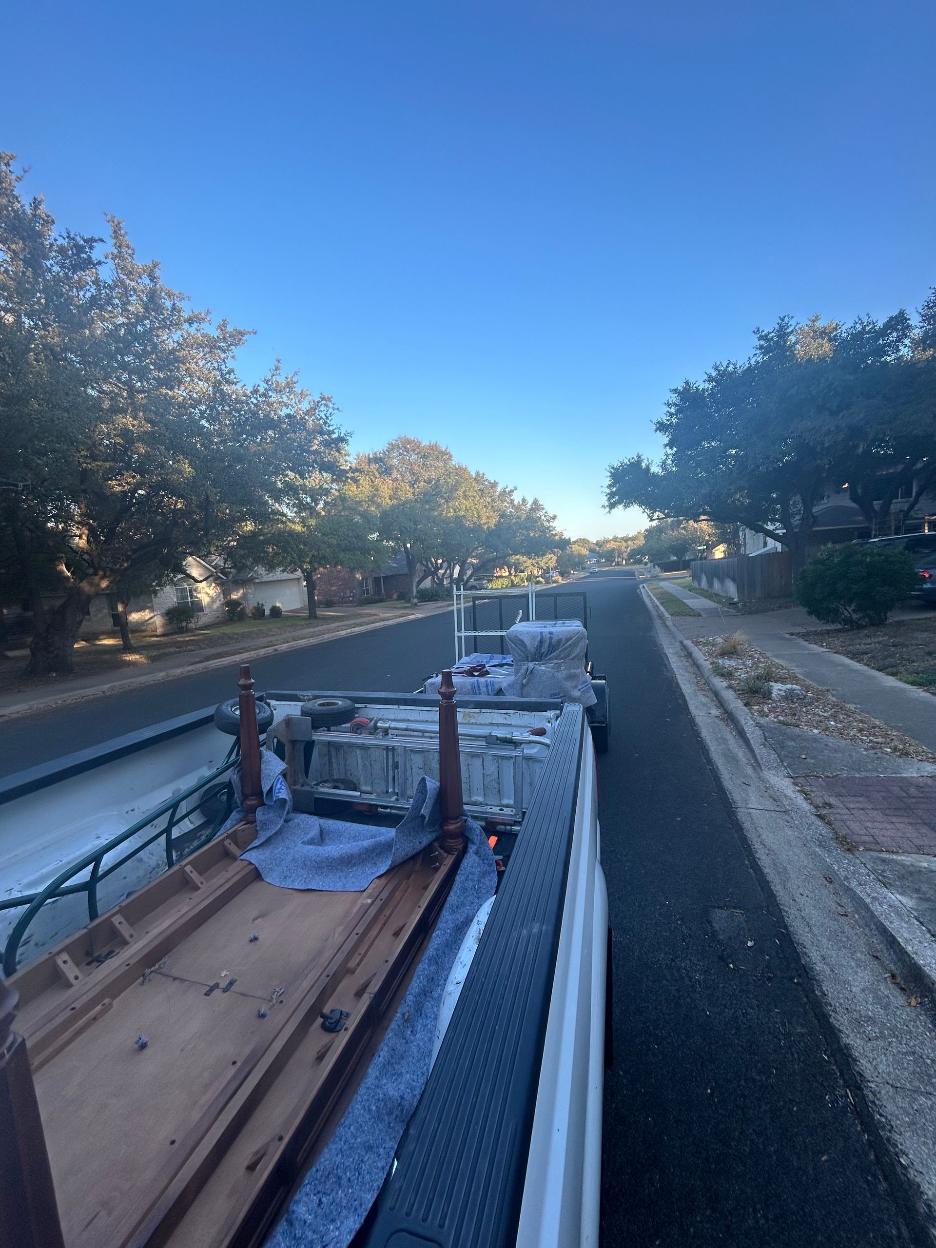 A truck is driving down a street with a bunch of furniture on the back of it.