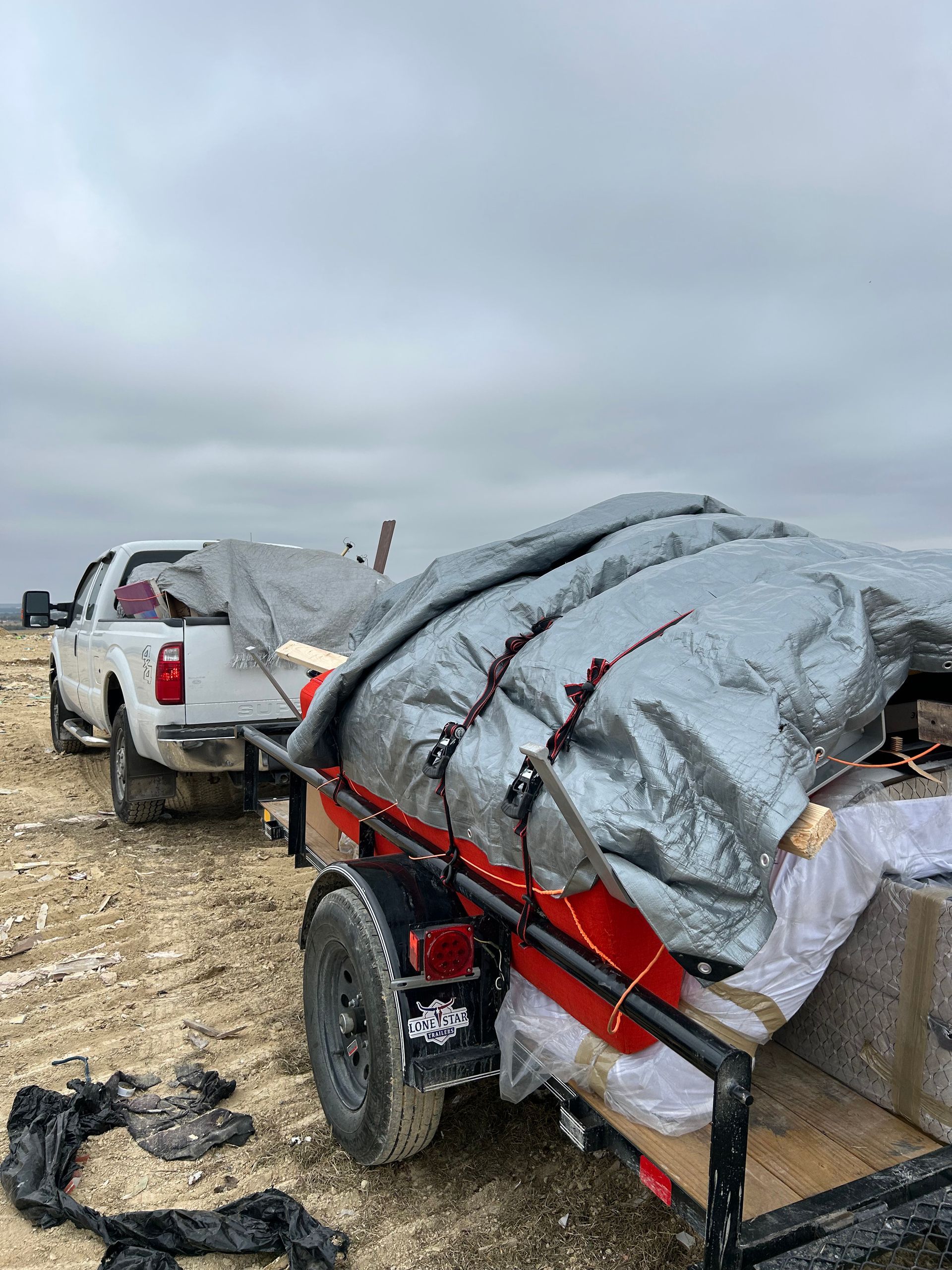 A truck is towing a trailer with a tarp on it.
