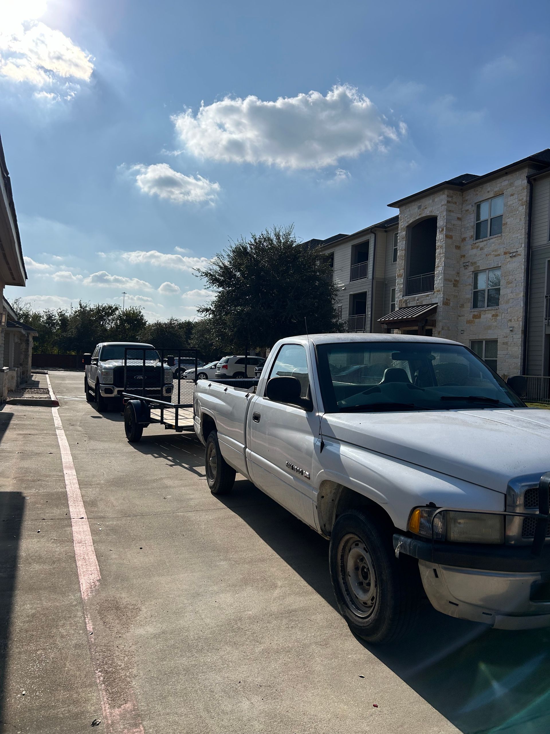 A white truck with a trailer attached to it is parked in a parking lot.