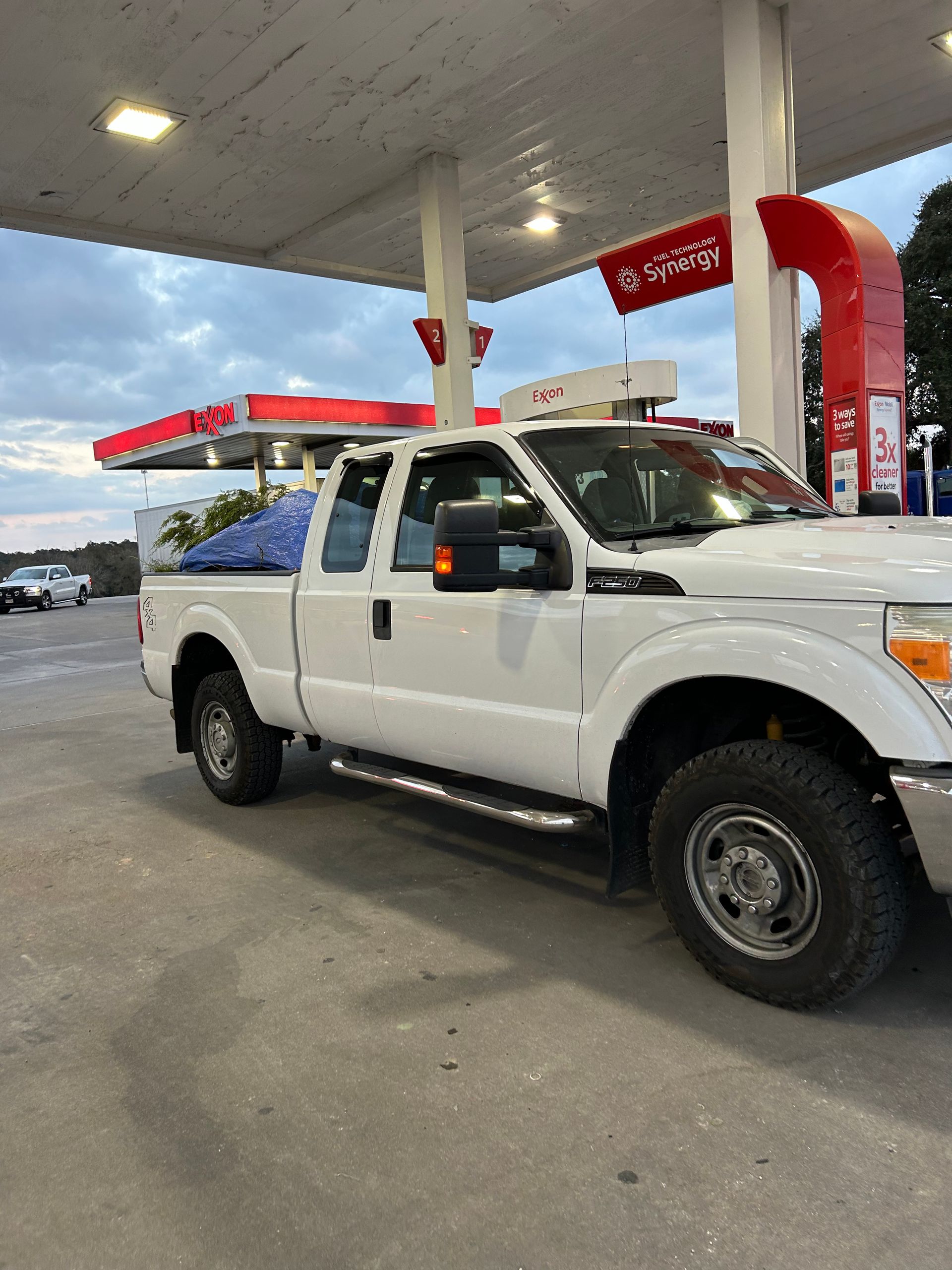 A white truck is parked at a gas station.