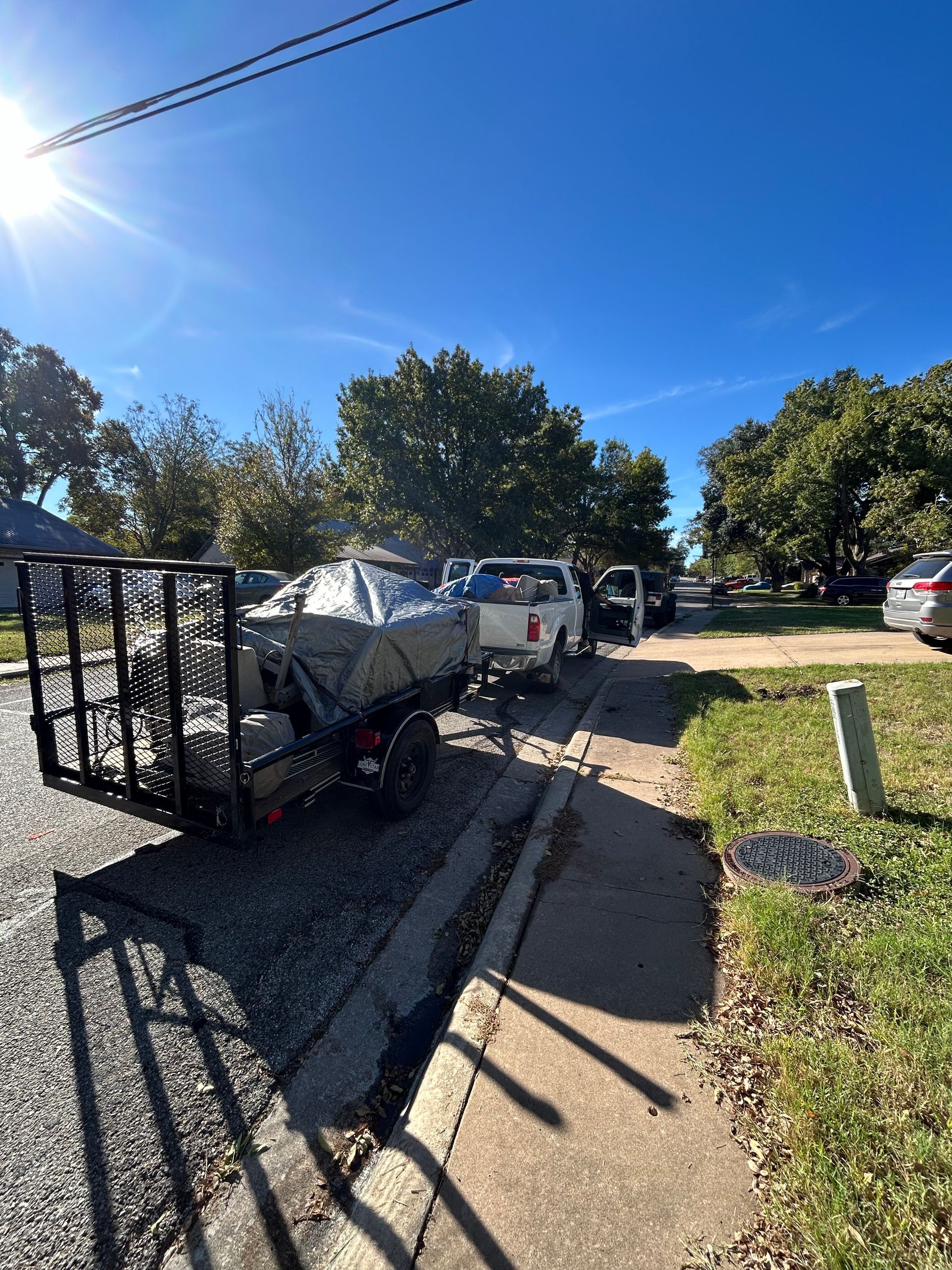 A trailer with a boat on it is parked on the side of the road.