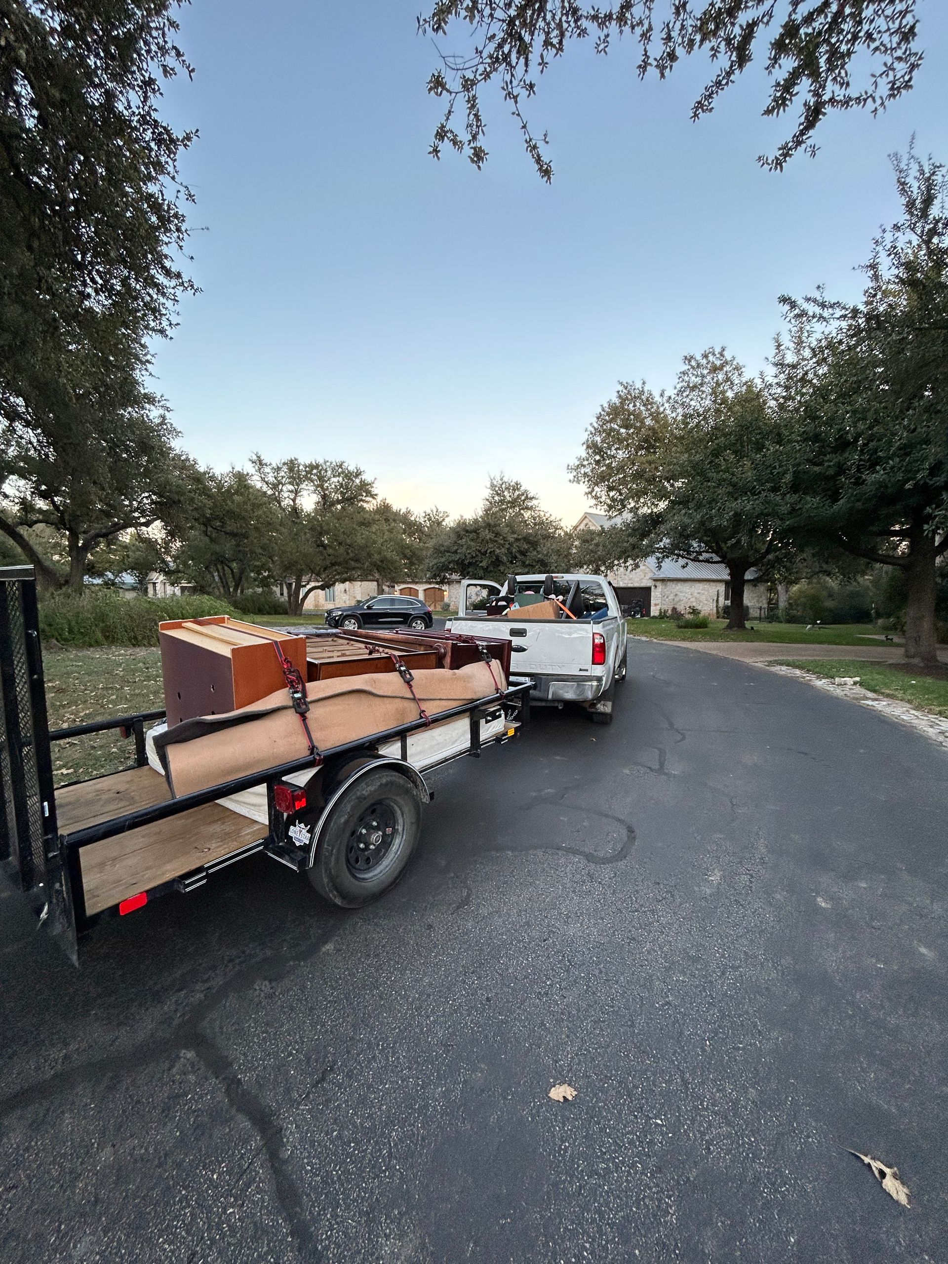 A truck is pulling a trailer full of furniture down a street.