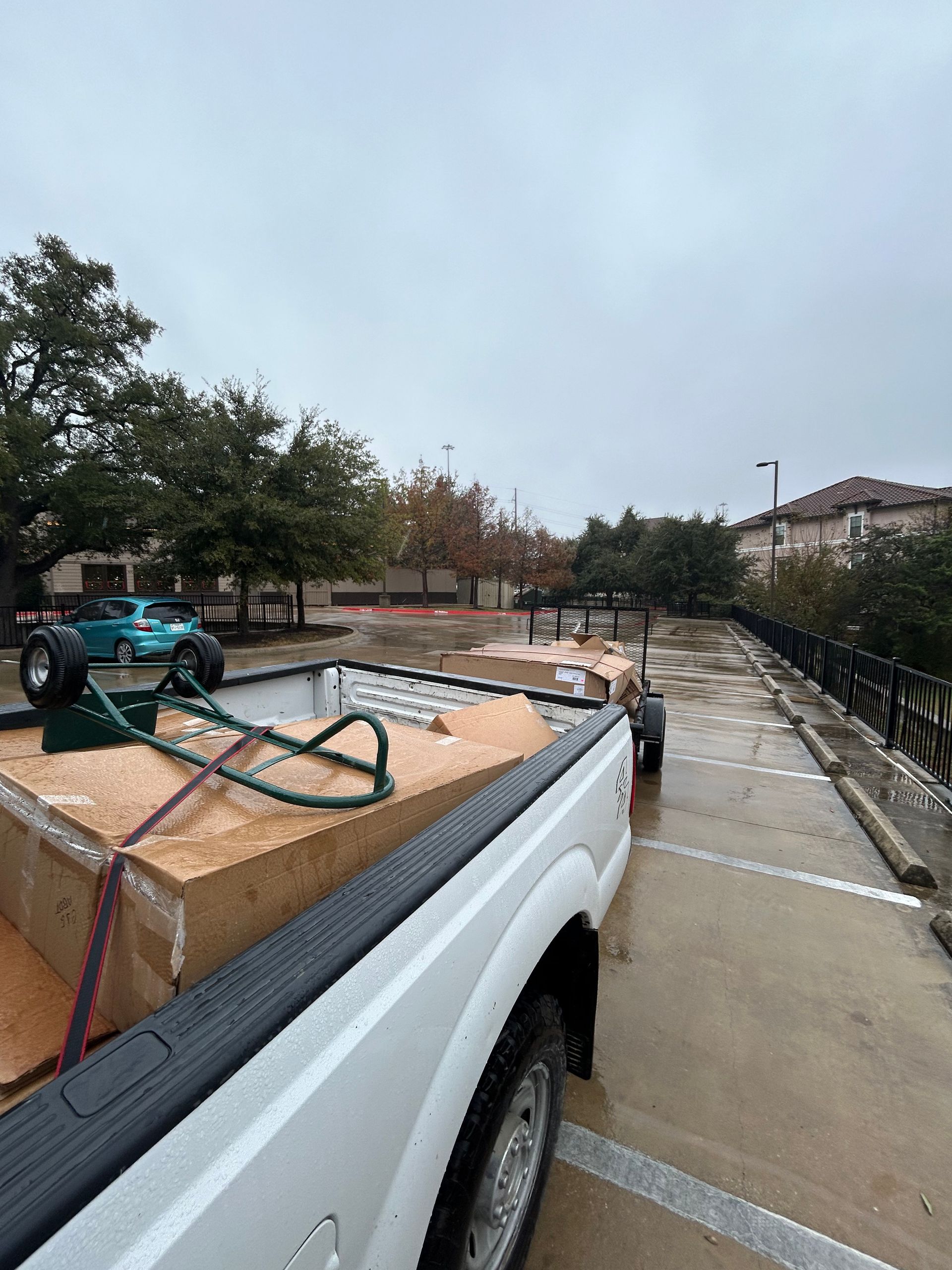 A white truck is parked in a parking lot with boxes in the back.