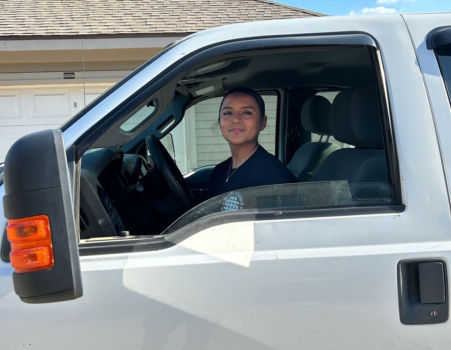 A woman is sitting in the driver's seat of a white truck.